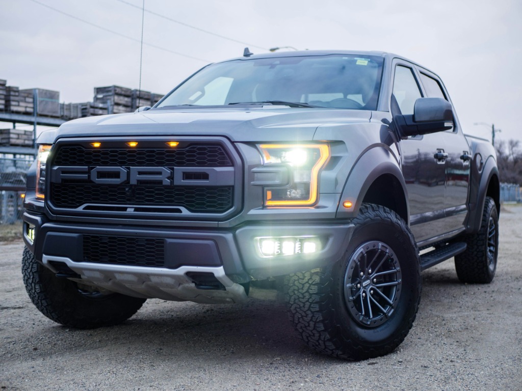 Ford Raptor crew cab truck with black running boards and all-terrain tires, front three-quarter view