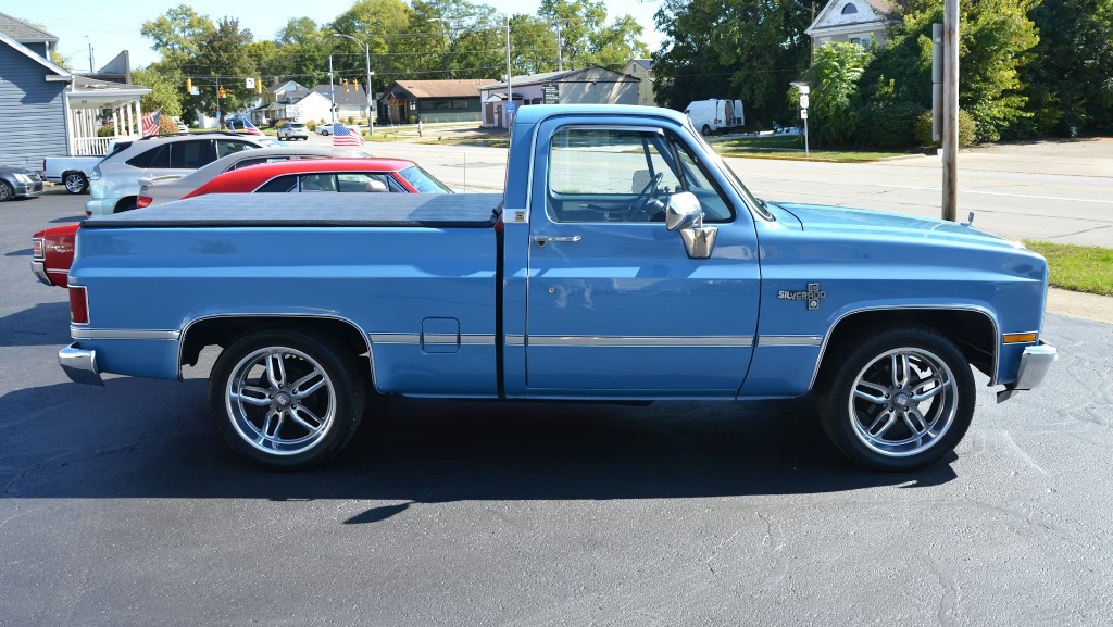 Blue Chevy Silverado regular cab pickup truck with a flush-mounted tonneau cover, side profile view